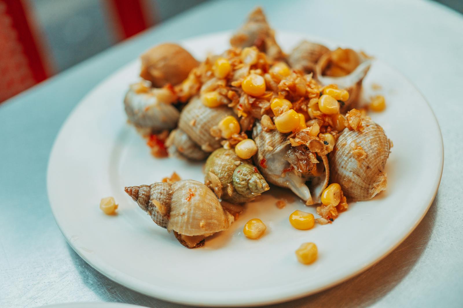 Plate of snails and corn garnished with spices, offering a gourmet seafood experience.